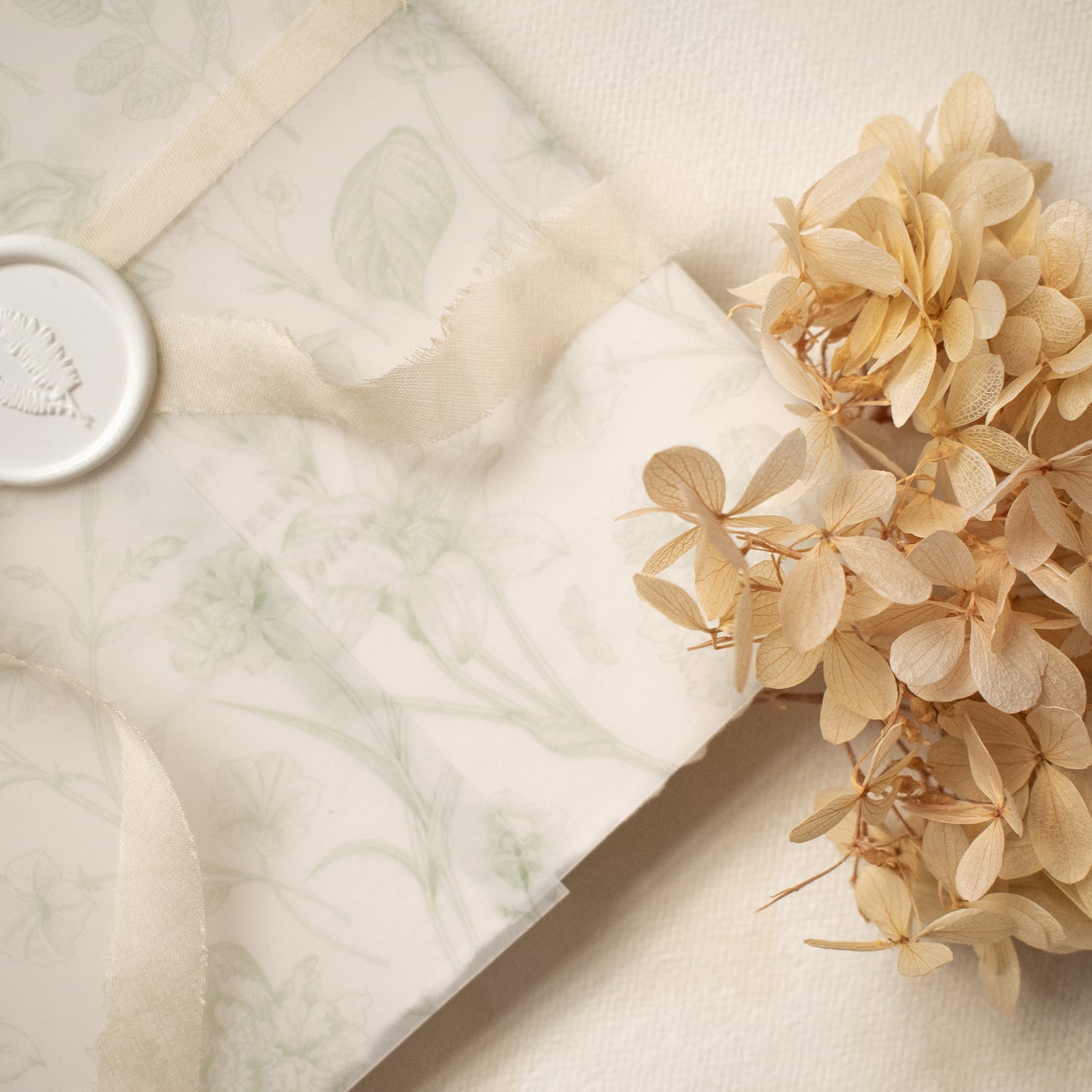 sage green floral vellum wrap with hand dyed silk ivory ribbon and white wax seal for wedding invitations