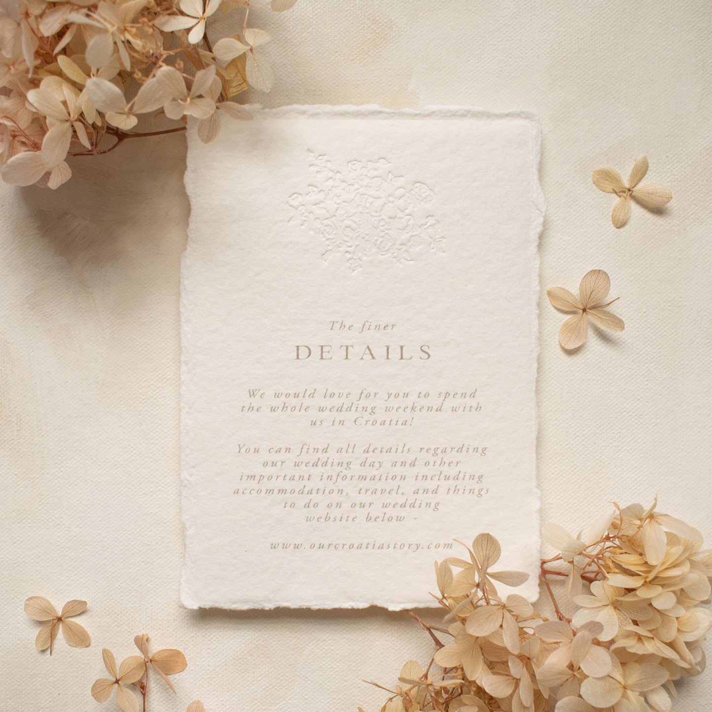 wedding details card with blind letterpress floral motif on handmade cotton paper, styled with dried flowers