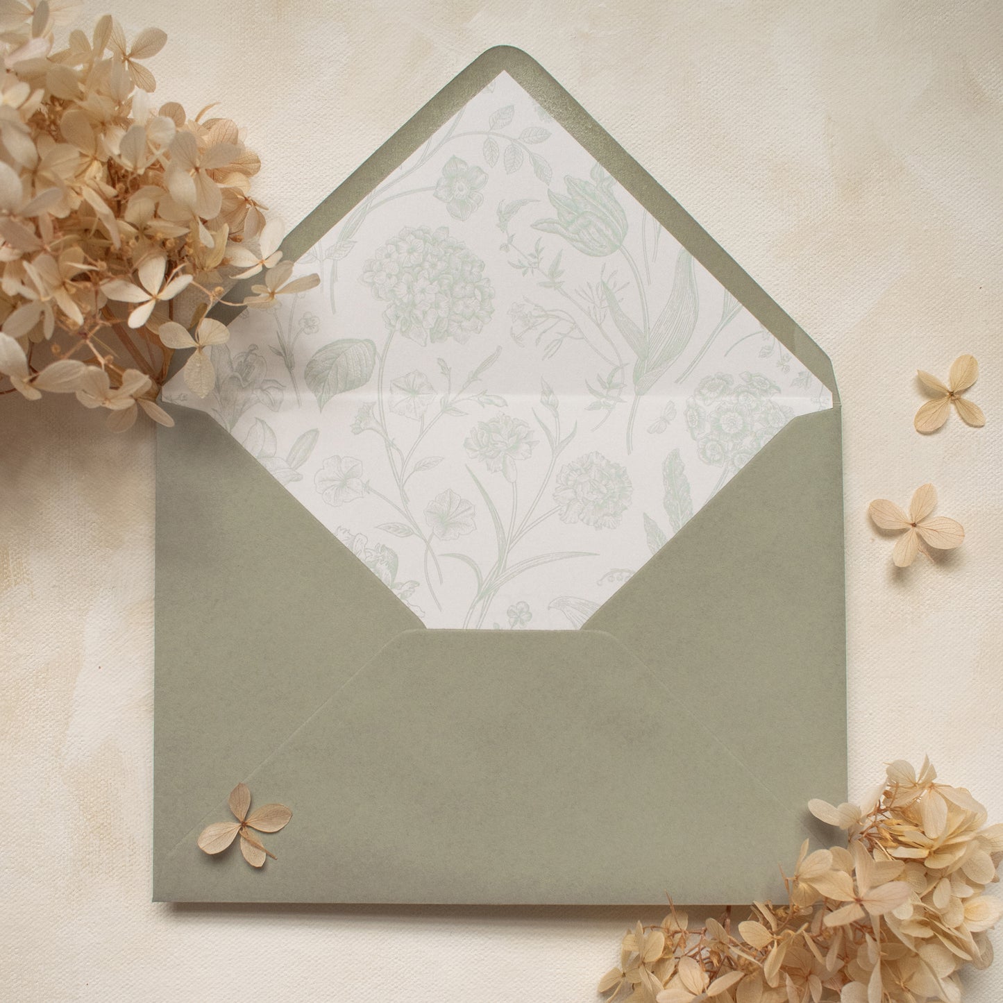 sage green envelope with matching floral patterned liner, styled with dried flowers